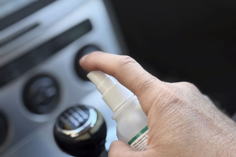 Hand spraying disinfectant inside a vehicle